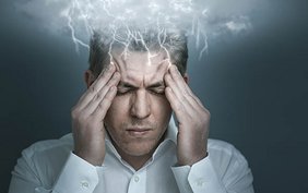 Mann mit Migräne, rund um seinem Kopf sind Blitze zu sehen